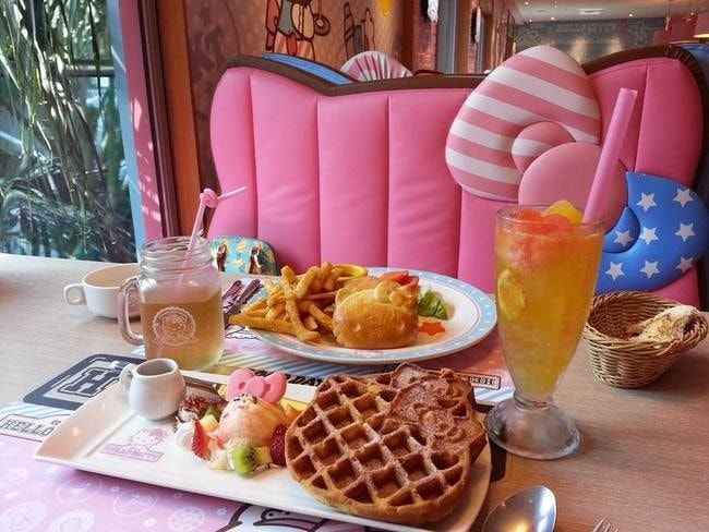 a table topped with waffles, fruit and other foods next to a glass of orange juice