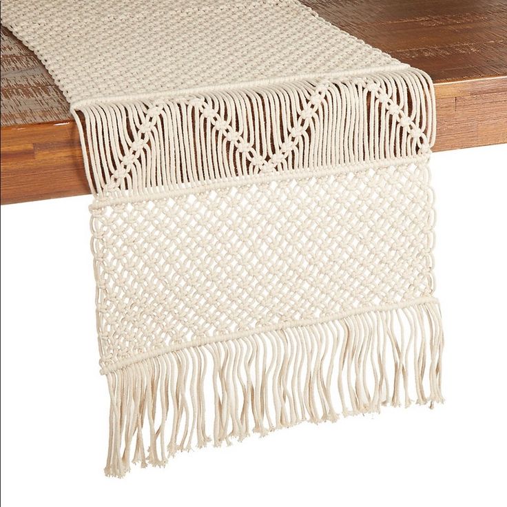 a table runner with fringes on it and a wooden table in the back ground