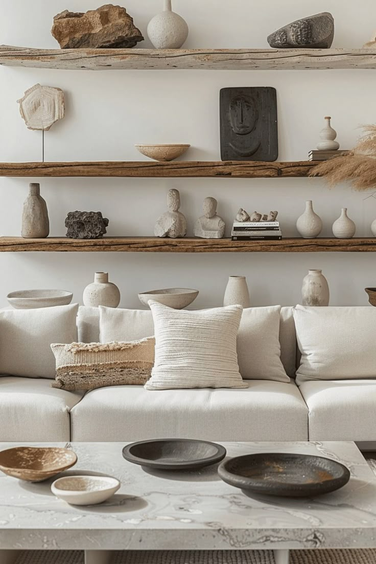 a living room filled with white furniture and lots of vases on the shelves above