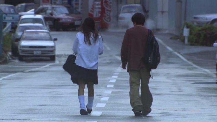 two people walking down the street in the rain