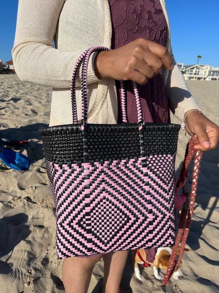 "This beautiful hand-woven, small tote is the latest creation of my business parter Cupertino. Handcrafted in Mexico. 9 1/2\"L x 9 1/2\"H x 5\"D; 16\" H with straps." Trendy Black Handwoven Bag, Trendy Black Handwoven Shoulder Bag, Black Handheld Handwoven Straw Bag, Rectangular Black Straw Bag With Woven Leather, Black Rectangular Straw Bag With Woven Leather, Casual Pink Handwoven Straw Bag, Black Woven Leather Straw Bag With Double Handle, Black Handwoven Shoulder Bag With Double Handle, Pink Rectangular Straw Bag For Everyday