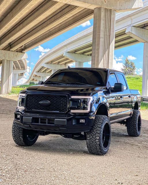 a black truck is parked under a bridge