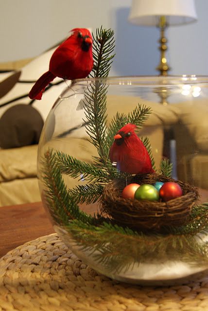 two red birds sitting on top of a glass bowl filled with water and christmas decorations