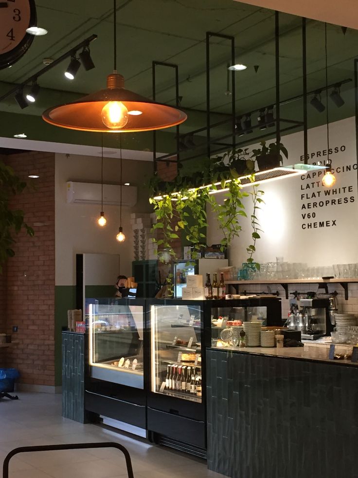 the interior of a coffee shop with plants hanging from the ceiling and lights above it