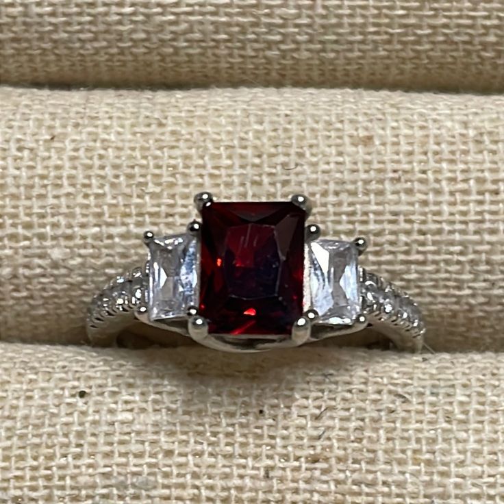 a red and white stone ring sitting on top of a piece of cloth