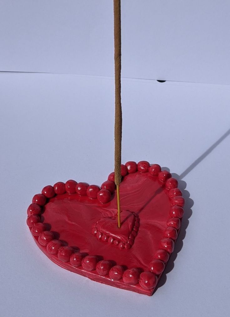 a red heart shaped object with a wooden stick sticking out of it's center