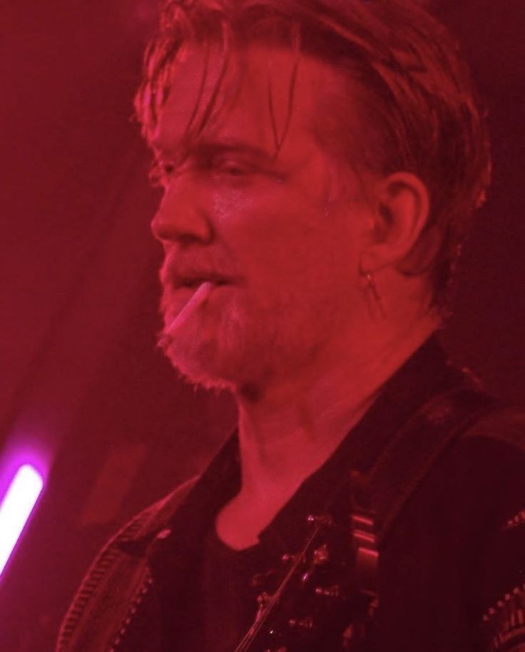 a man standing in front of a red light with his mouth open and tongue out