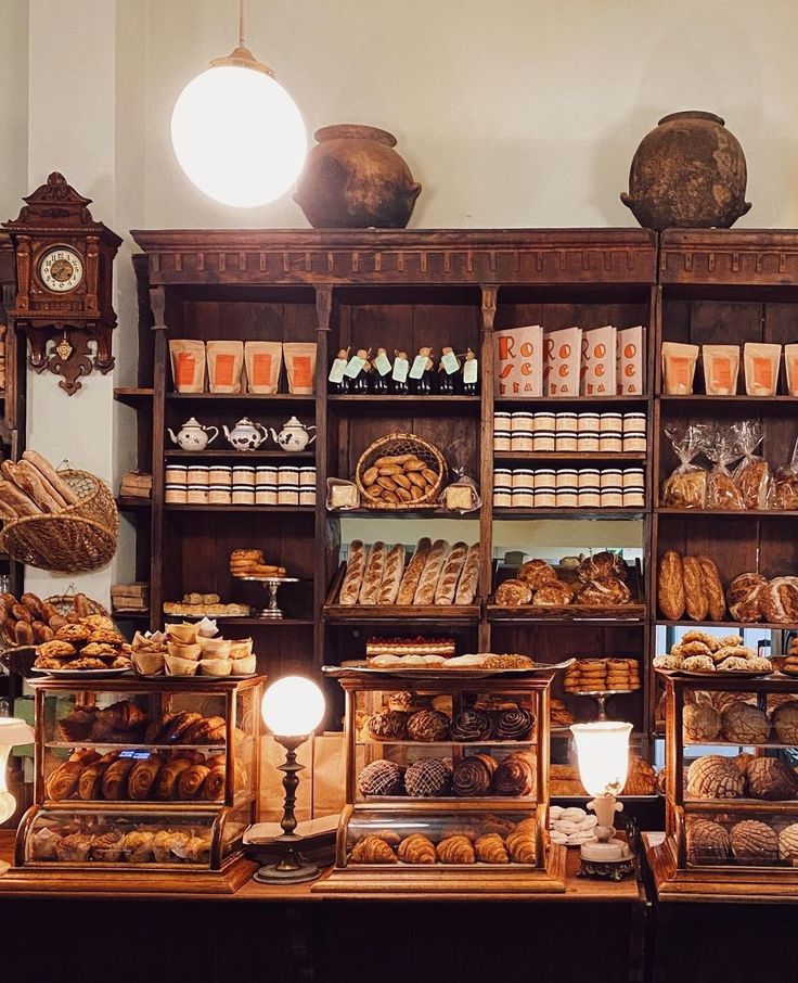 an assortment of breads and pastries on display in a bakery shop with wooden shelves