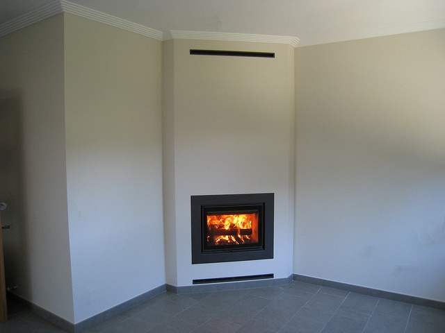 an empty room with a fire place in the corner