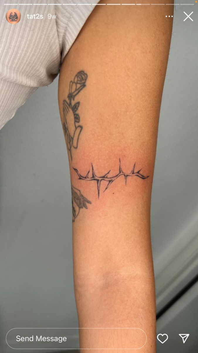 a person with a tattoo on their arm and the word love written in barbed wire