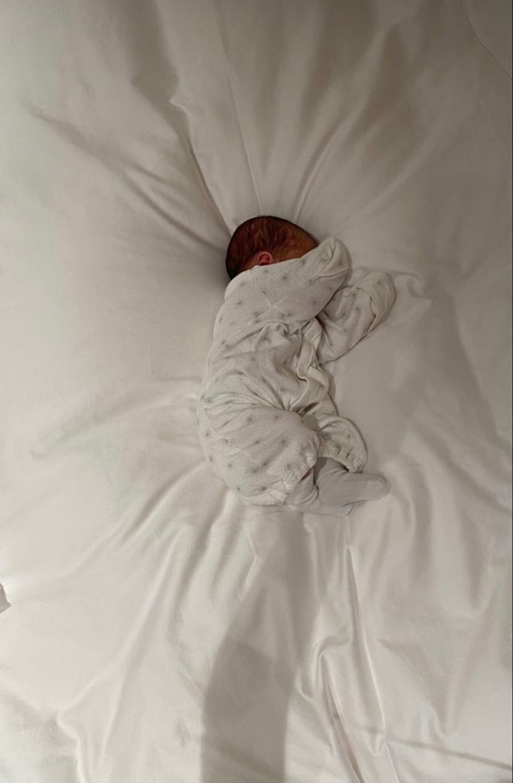 a baby is sleeping on a white blanket