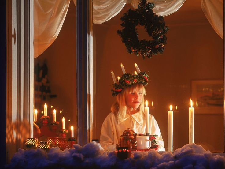 a woman sitting at a table with candles in front of her and looking out the window