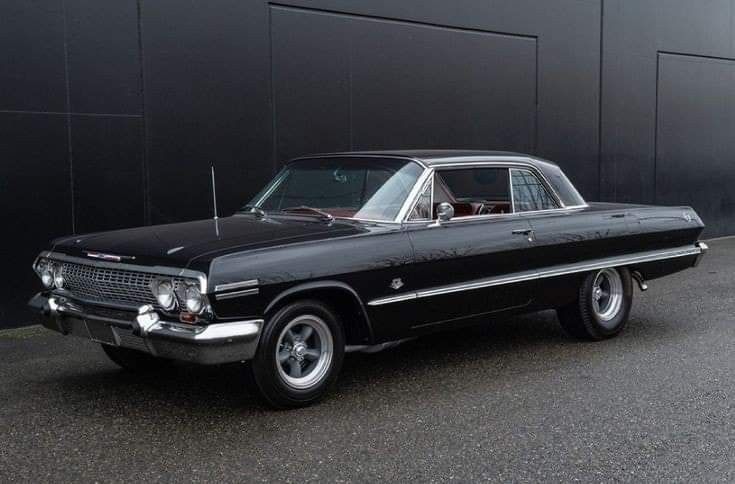 an old black car parked in front of a building