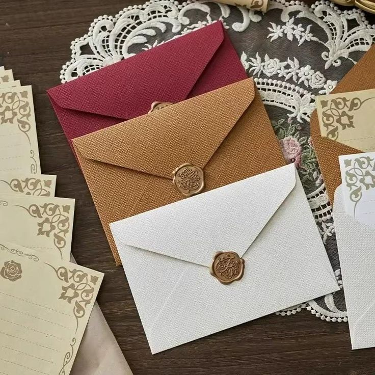 several envelopes are sitting on a lace doily and some cards have been placed next to each other