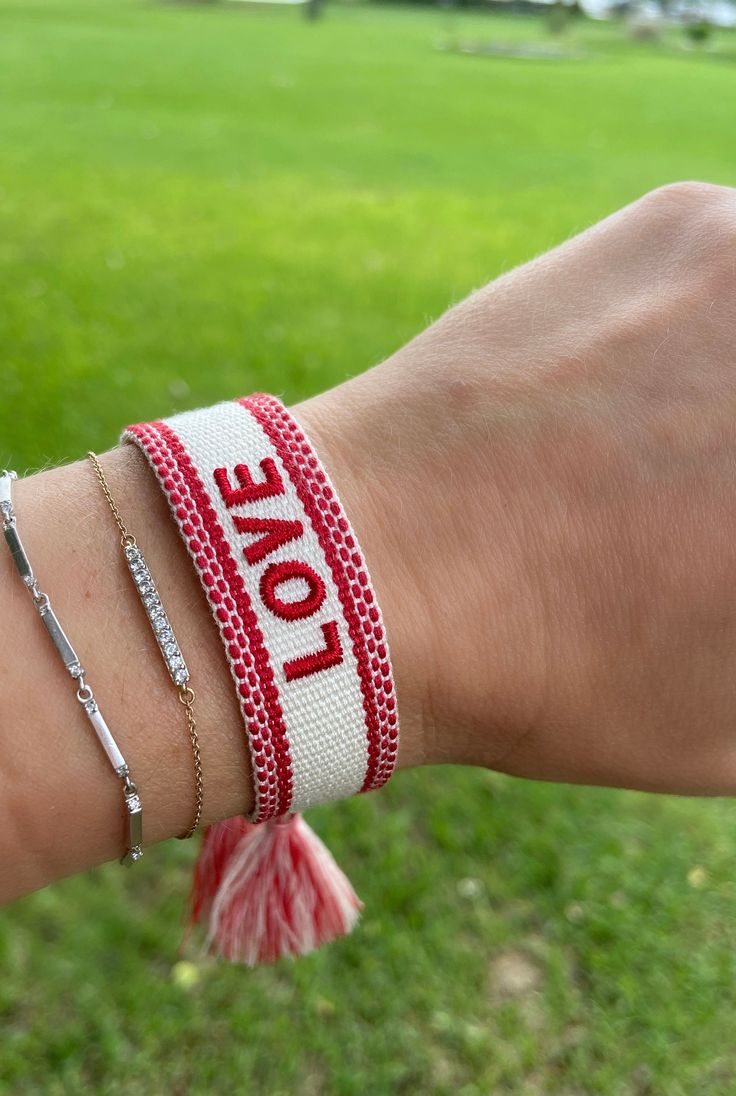 a person is wearing two bracelets with the word love written on them in red and white