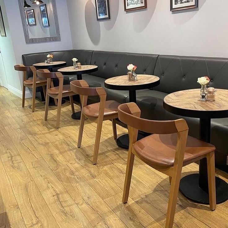 several tables and chairs in a restaurant with wood flooring on one side and white walls on the other