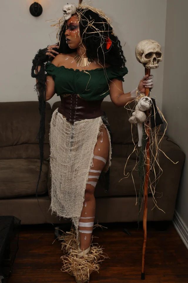 a woman dressed up as a skeleton holding a stick and a skull in her hand