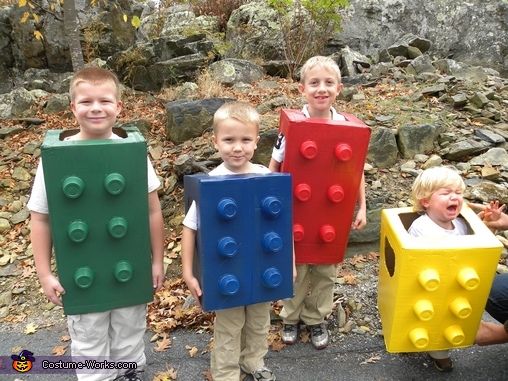 four children with legos on their heads standing in front of some rocks and trees