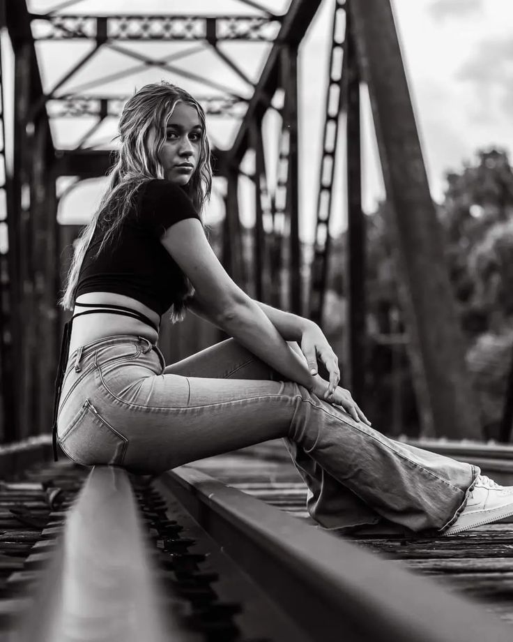 Black and white. Railroad bridge. Jeans and a black half shirt. Blonde girl sitting on railroad bridge. Photoshoot Railroad Tracks, Senior Pics On Train Tracks, Poses On Railroad Tracks, Photoshoot On Railway Track, Senior Picture Ideas On Railroad Tracks, Cute Senior Photoshoot Ideas, Female Senior Picture Poses Photo Ideas, Railroad Track Photoshoot Senior Pics, Senior Pictures Women