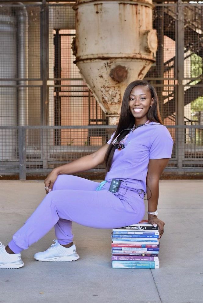 a woman sitting on top of a stack of books in front of a metal structure