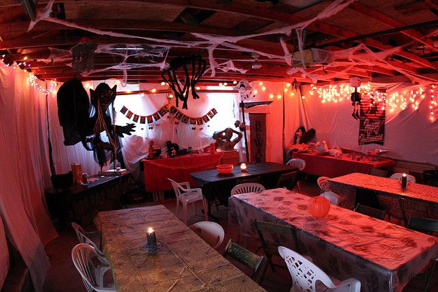 a room filled with tables and chairs covered in halloween decorations on the ceiling above them