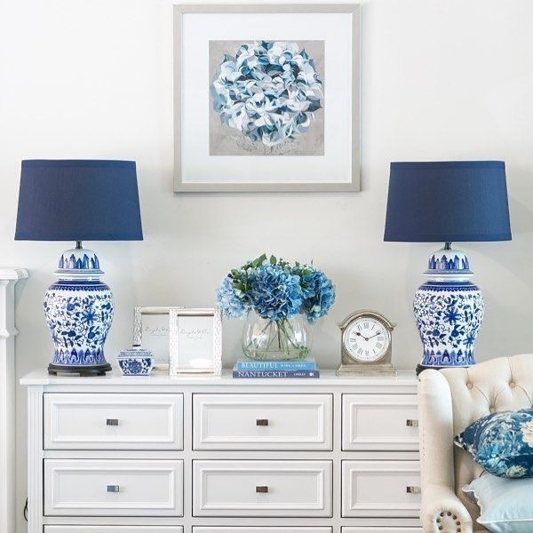 two blue and white vases sitting on top of a dresser next to a clock