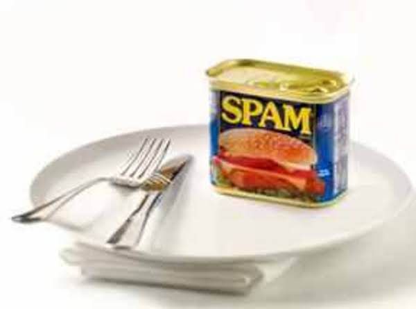 a can of spam sitting on top of a white plate next to a fork and knife