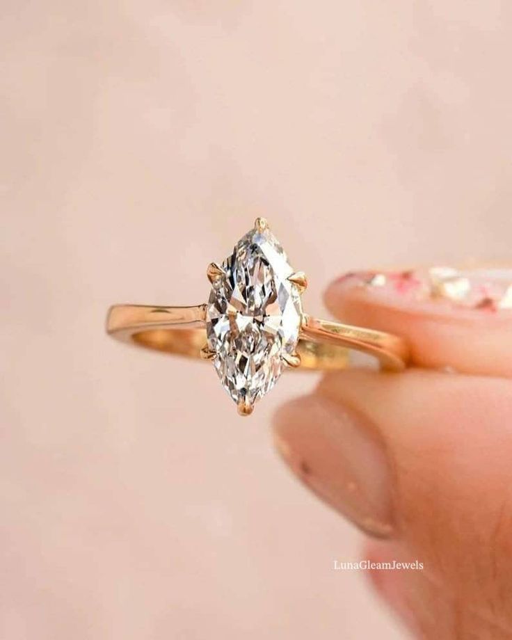 a person holding an engagement ring with a diamond in it's center and the other hand