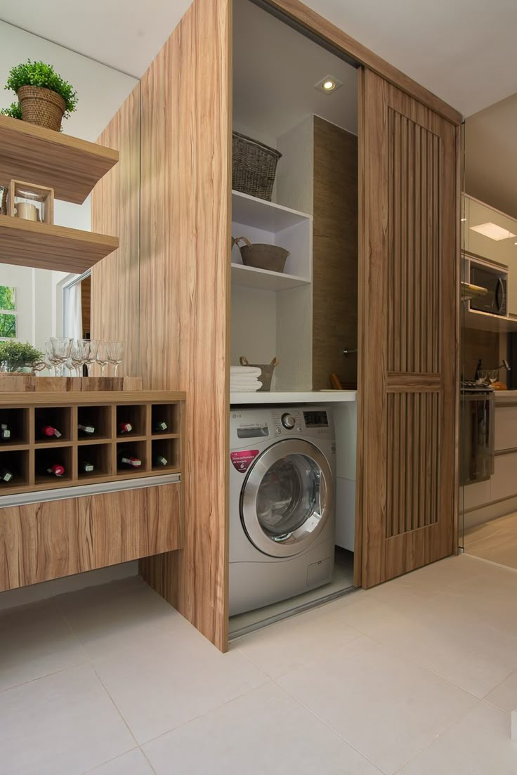 a washer and dryer in a small room with open shelves on the wall