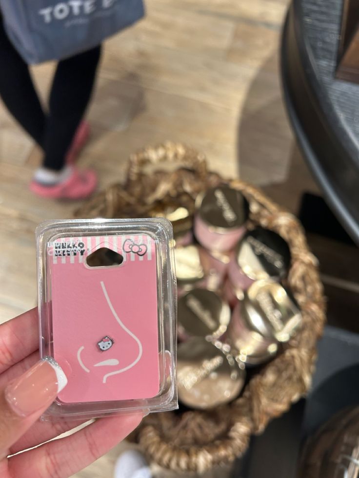 a person holding up a pink phone case in front of a basket full of shoes