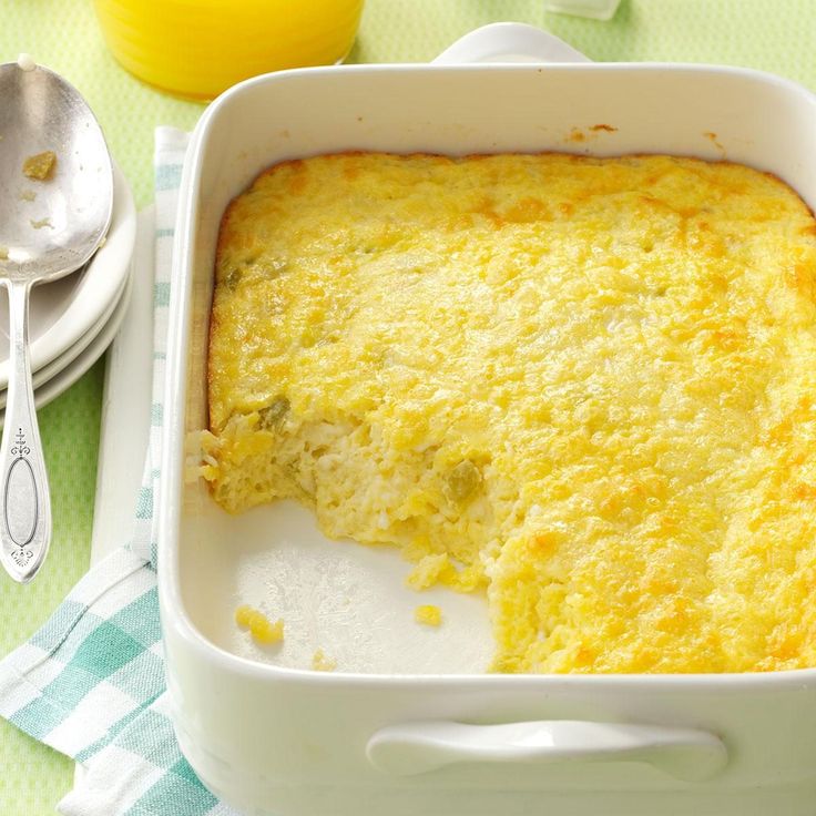 a casserole dish on a green table cloth with a spoon next to it