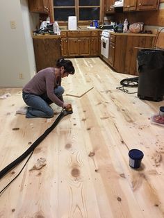 a woman kneeling on the floor working on wood