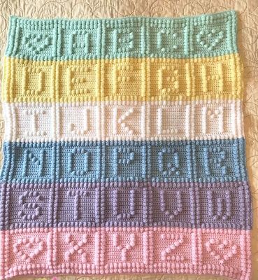 a crocheted blanket with numbers and letters in different colors on top of it