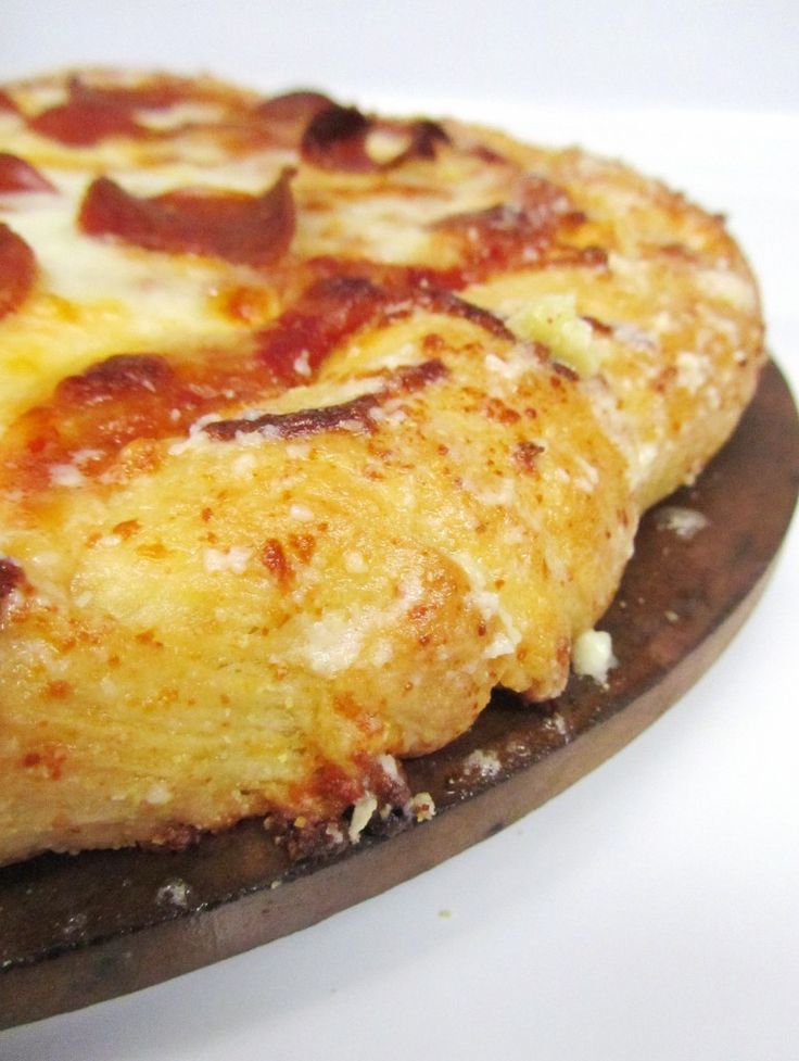 a pizza sitting on top of a wooden plate covered in cheese and pepperoni toppings