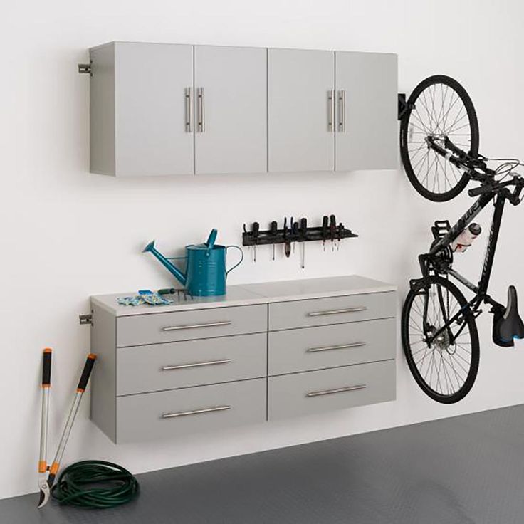 there is a bike hanging on the wall next to some cupboards and a toolbox