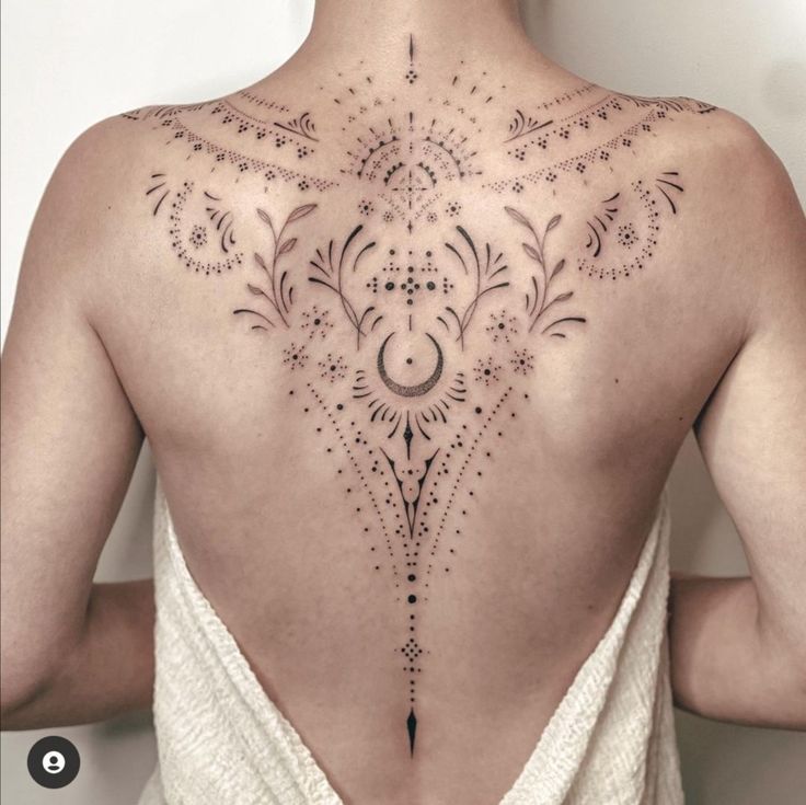 the back of a woman's neck with an intricate tattoo design on her left side