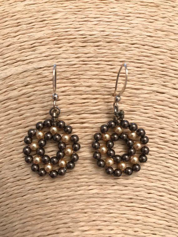 the earrings are made out of beads and silver metal wire, on top of a wicker basket