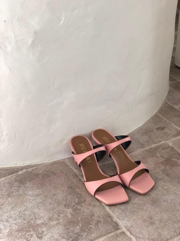 a pair of pink and black shoes sitting on the floor next to a white wall