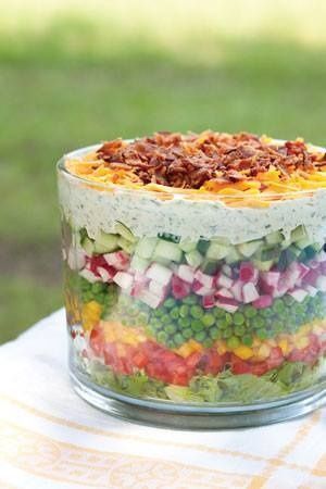 a layered salad in a glass dish on top of a table