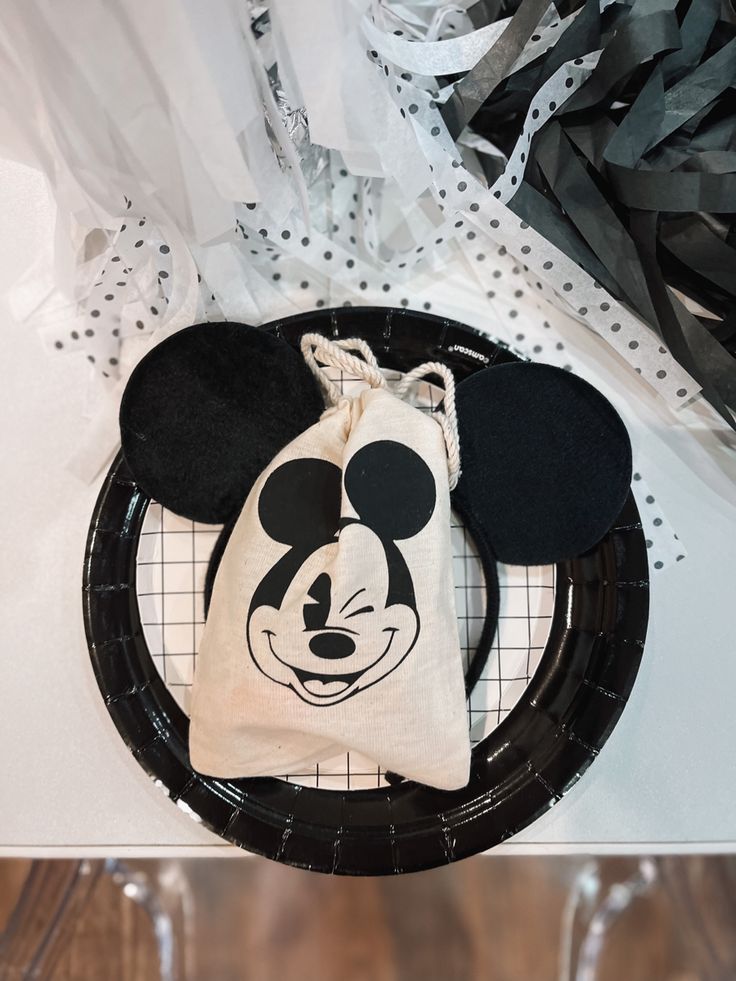 a mickey mouse bag sitting on top of a black plate next to a white paper bag