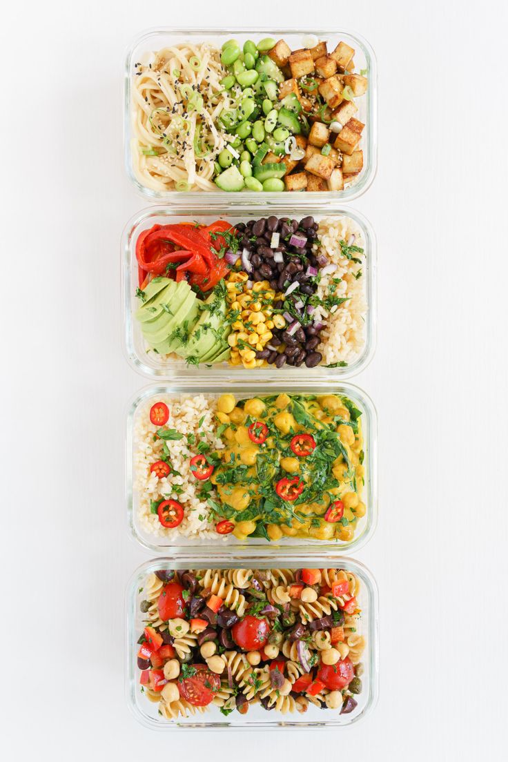 three plastic containers filled with different types of salads and pasta, all on top of each other