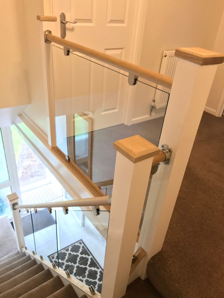 a stair case with glass railing and wooden handrail