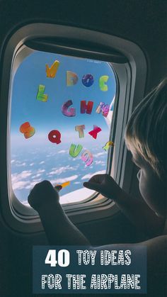 a little boy looking out an airplane window at the clouds and letters that spell out