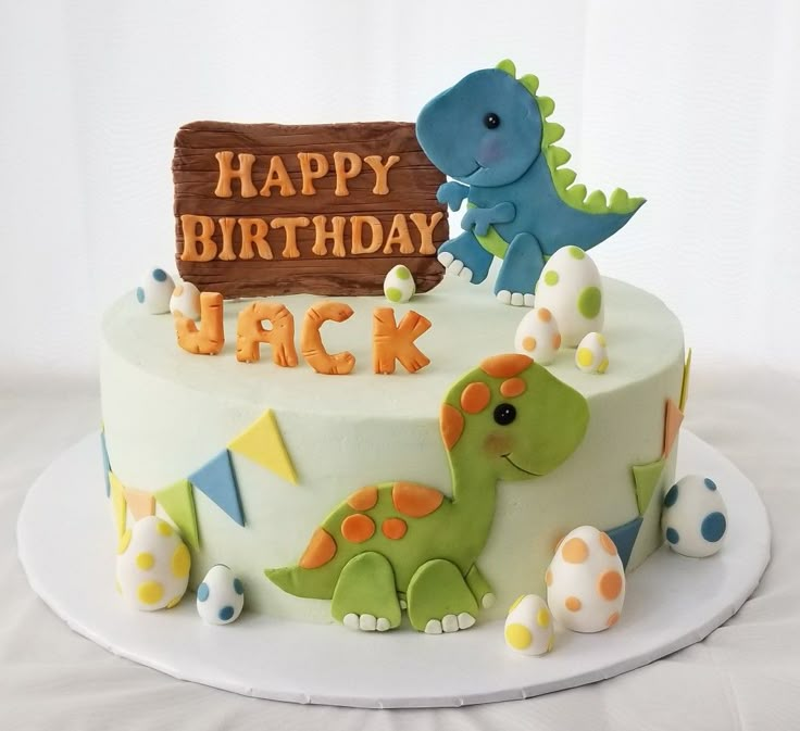 a birthday cake decorated with dinosaurs and a sign that says happy birthday jack