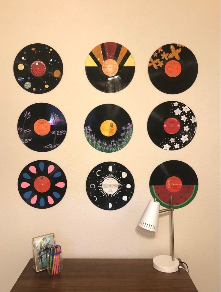 there are many different records on the wall next to a lamp and a table with books