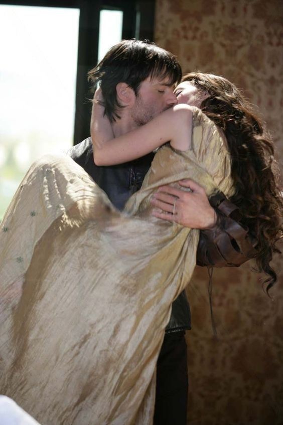 a man and woman embracing each other in front of a window