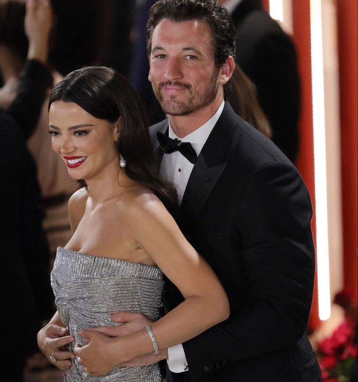 a man in a tuxedo hugging a woman on the red carpet at an event