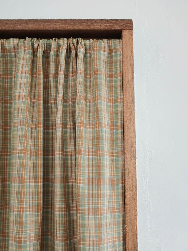 a window with a curtain hanging on it's side in front of a white wall