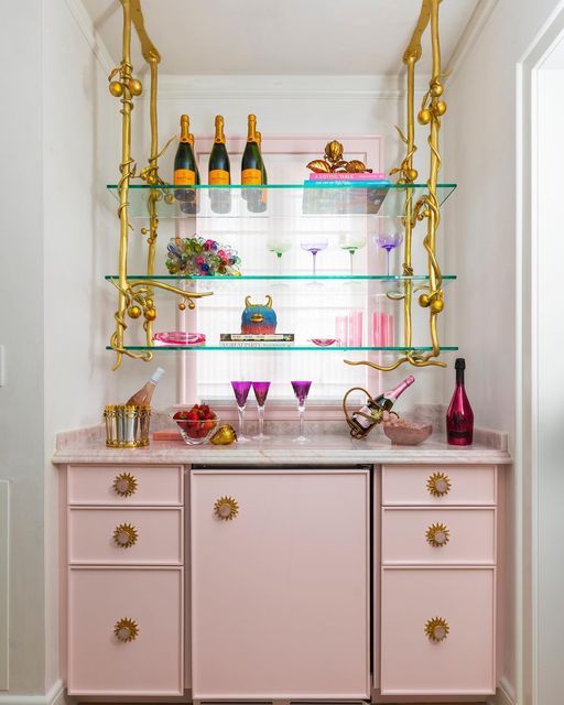 a pink and gold bar with lots of bottles on the top, shelves above it