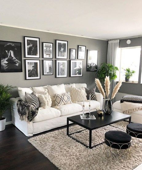 a living room filled with white furniture and pictures on the wall above it's coffee table